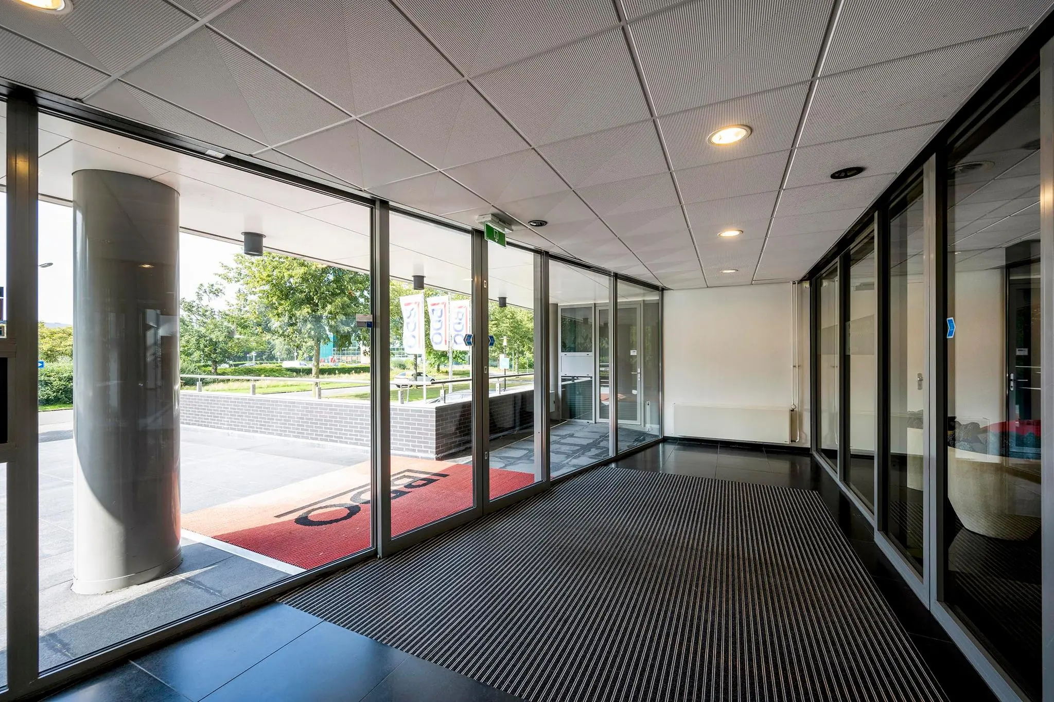 Inkomhal met glazen schuifdeuren en uitzicht op de K.P. van der Mandelelaan in Rotterdam.